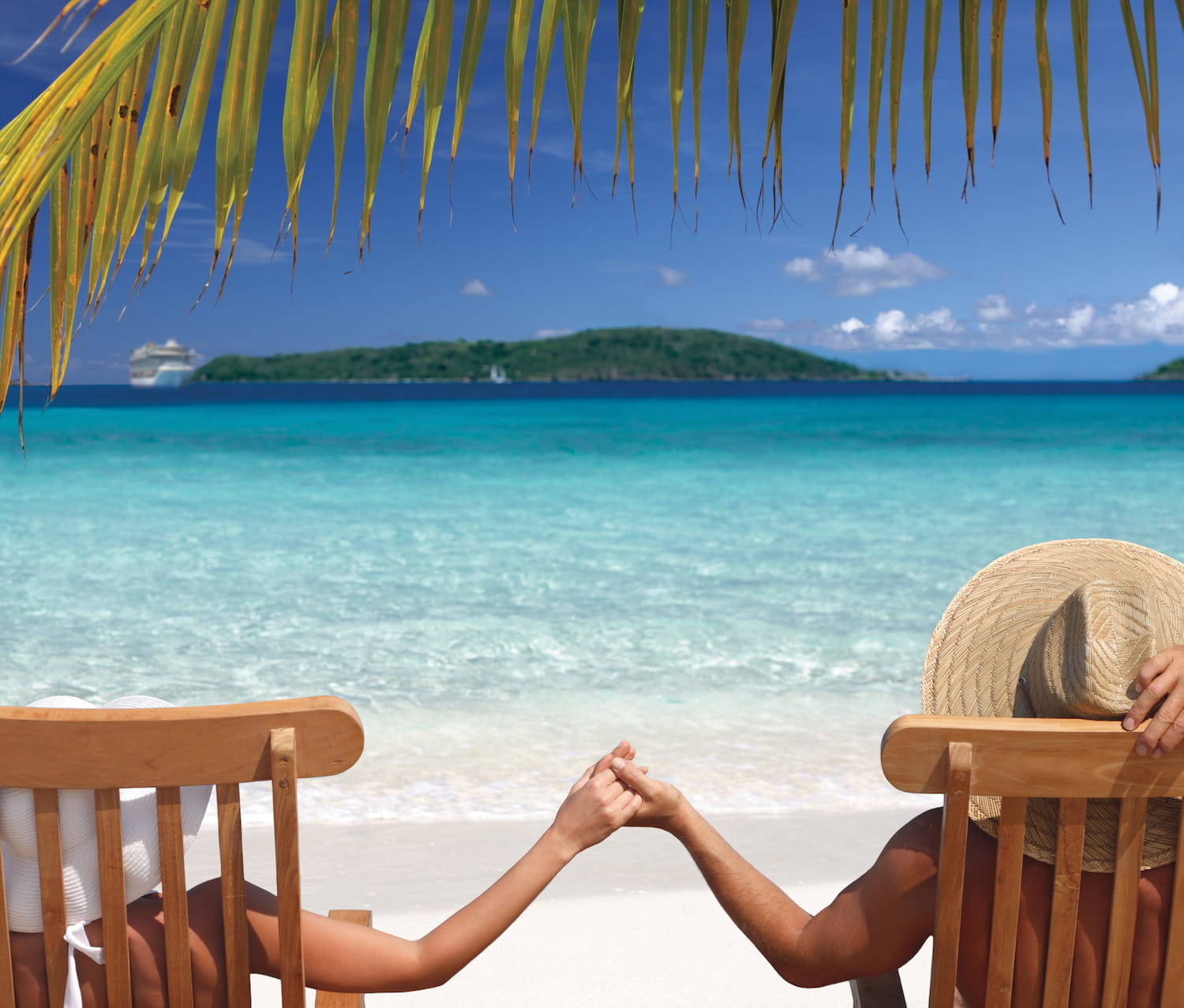 Two people sitting in chairs, holding hands and looking out at the ocean